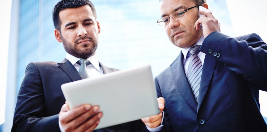 Experienced businessmen discussing details of the project and negotiating with their client on the phone
